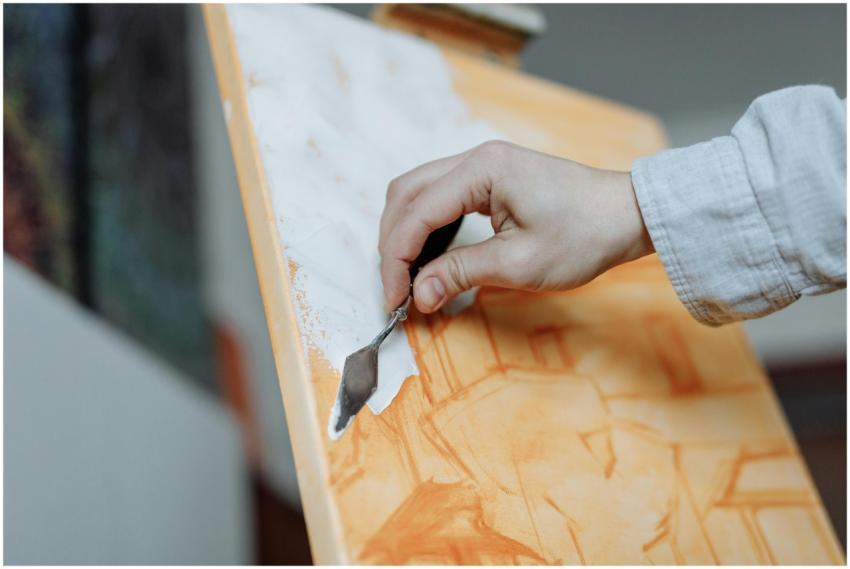 Hand using a palette knife for an abstract paintin