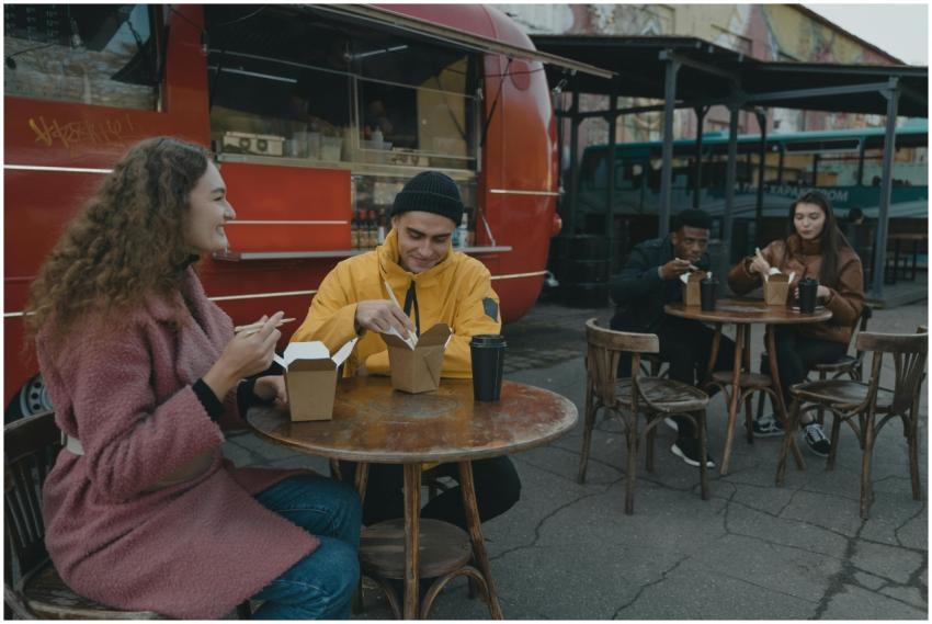 Friends enjoy a meal at an outdoor food truck area