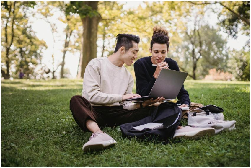 Two young men studying on a laptop while sitting o