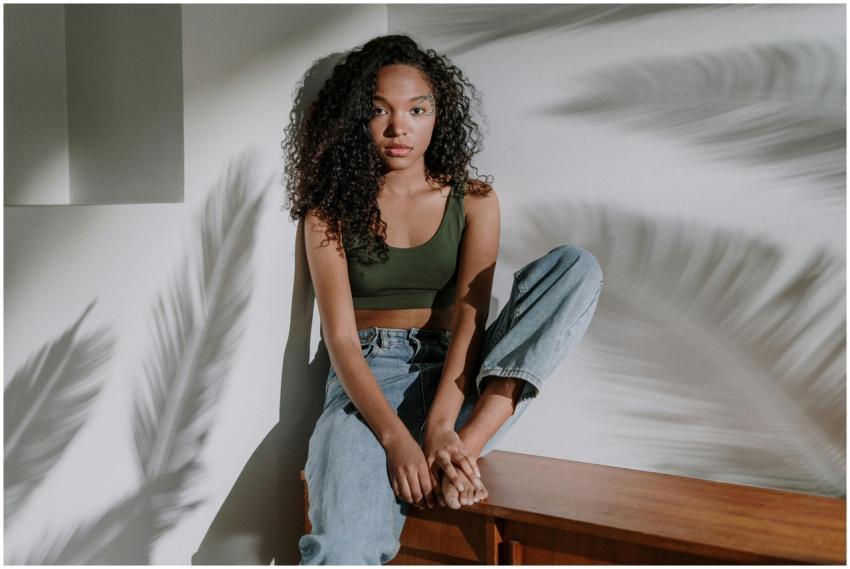 A young woman with curly hair sits peacefully indo
