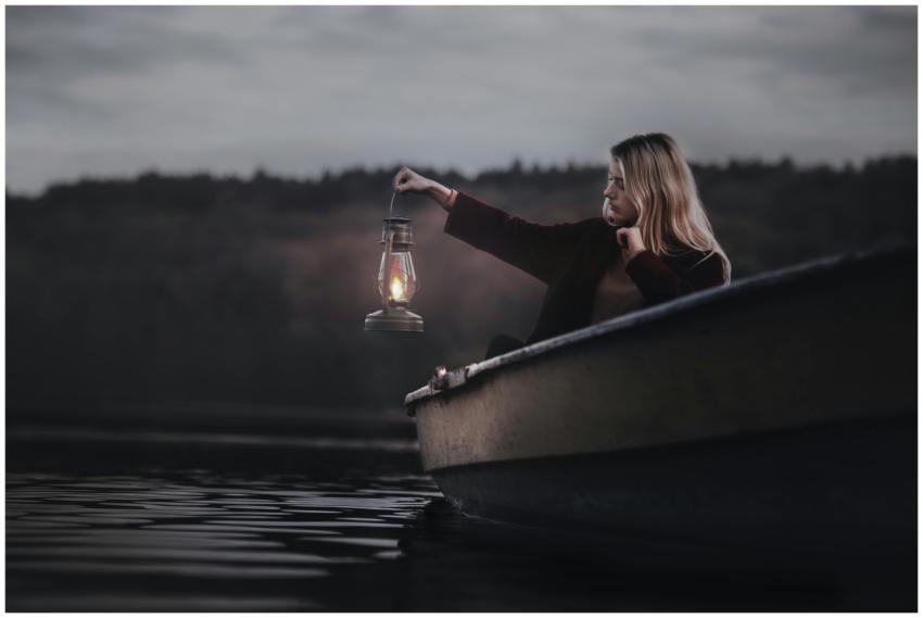 A contemplative woman in a boat holding a lantern