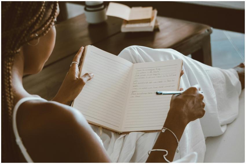 A black woman writes in a notebook, enjoying a cal