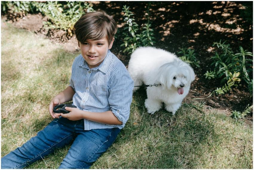 A young boy sitting in the grass with his fluffy w