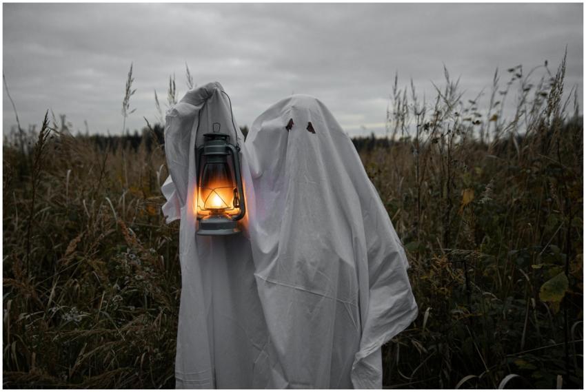 A ghostly figure holds a lantern in a dark, spooky