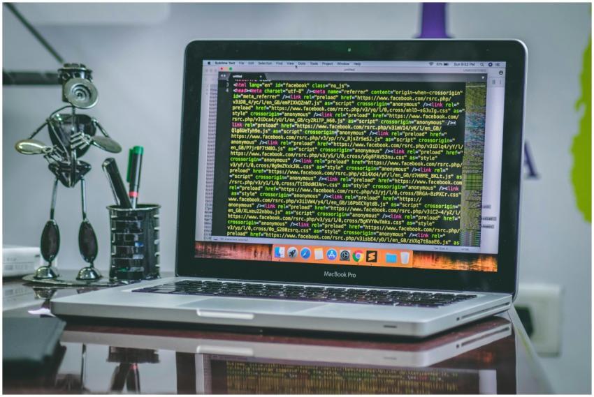 A sleek MacBook Pro displaying code on a desk with