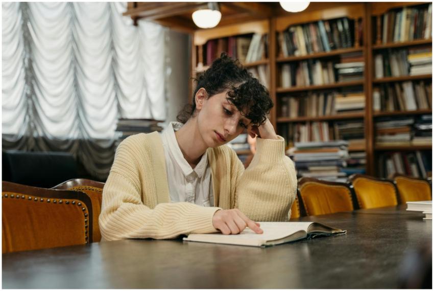 A young woman reading a book while studying indoor