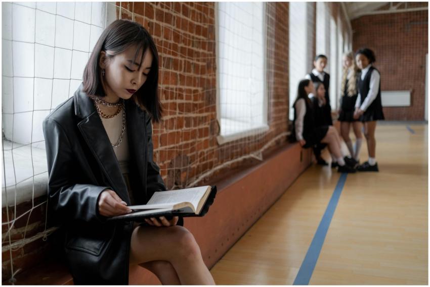Teenager in leather jacket reads amid classmates i