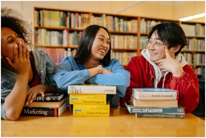Three diverse students laughing and studying toget