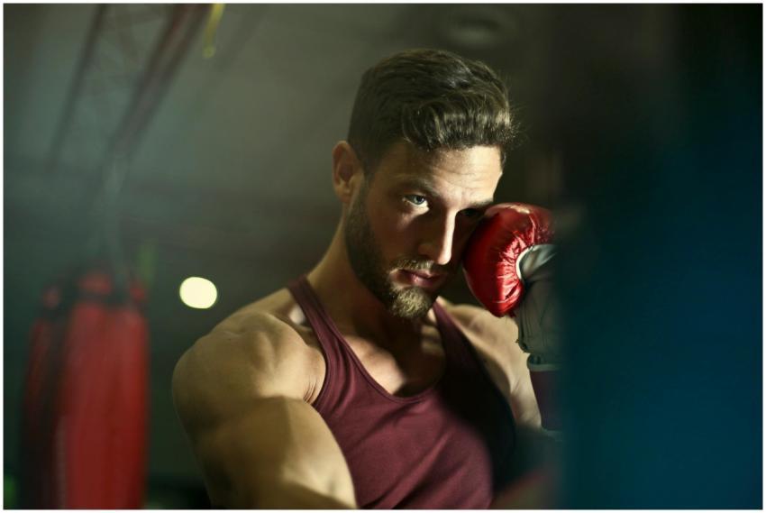Bearded male boxer in gym focusing intensely durin