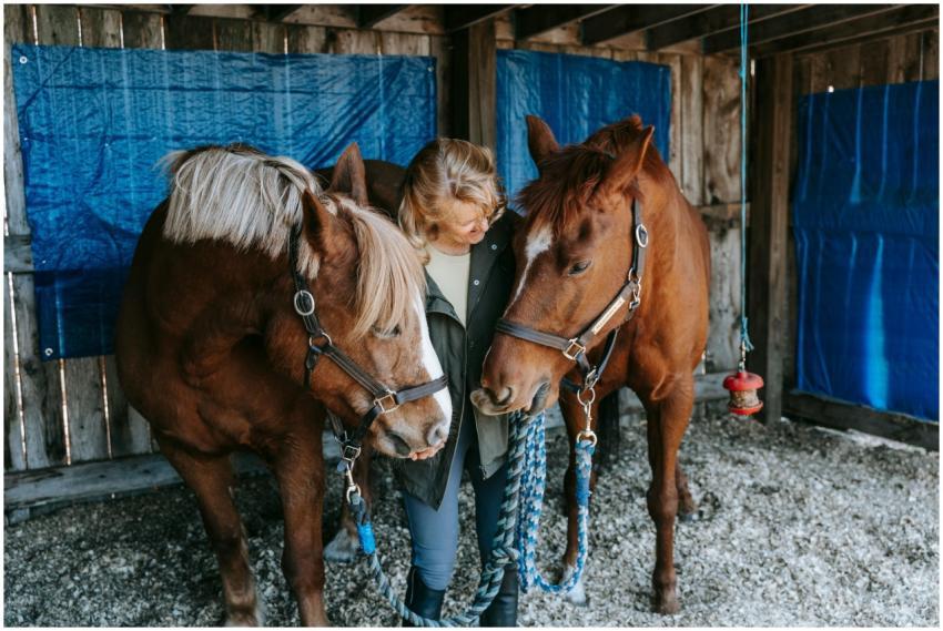 A woman enjoys a peaceful moment with two horses i