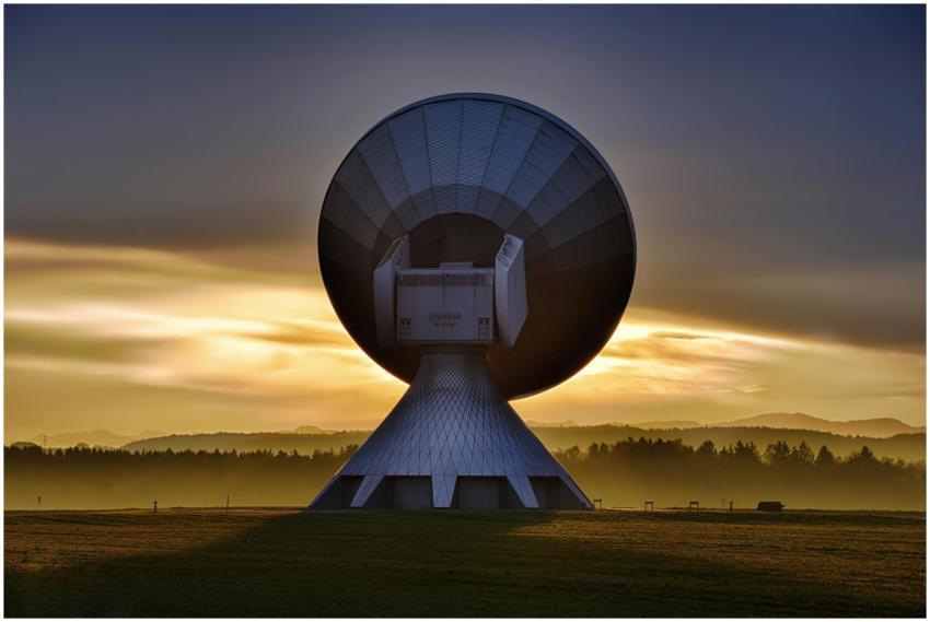 Large satellite dish silhouette against a colorful