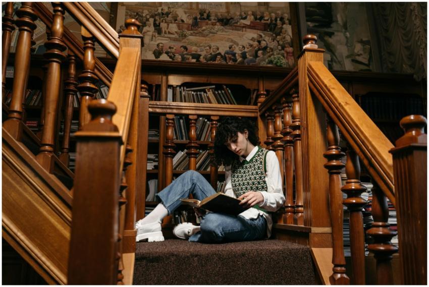 A person reading a book on wooden stairs surrounde