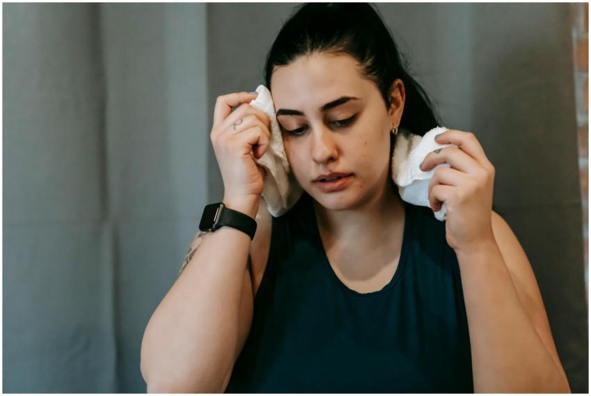 Woman wiping sweat with a towel, taking a break af