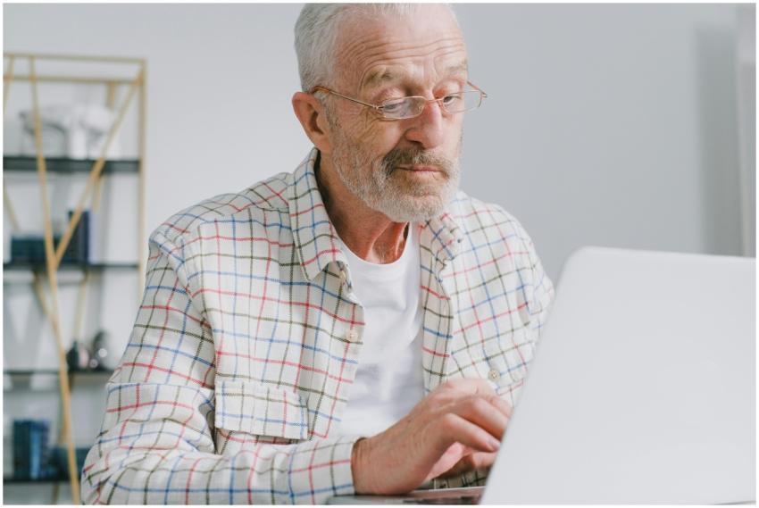 Senior man with eyeglasses working on a laptop in