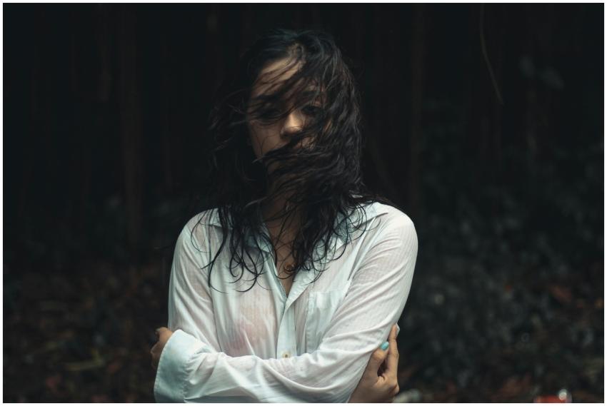 Moody portrait of a woman with wet hair in a fores
