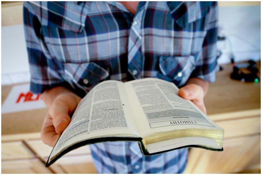 A person holding and reading an open Bible, focusi