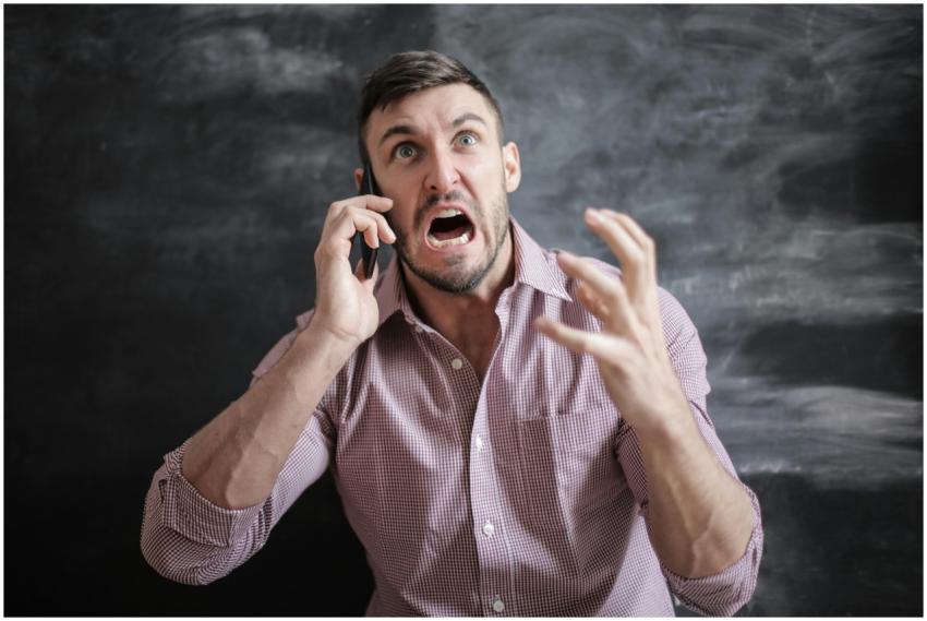 A distressed man in a pink shirt expressing frustr