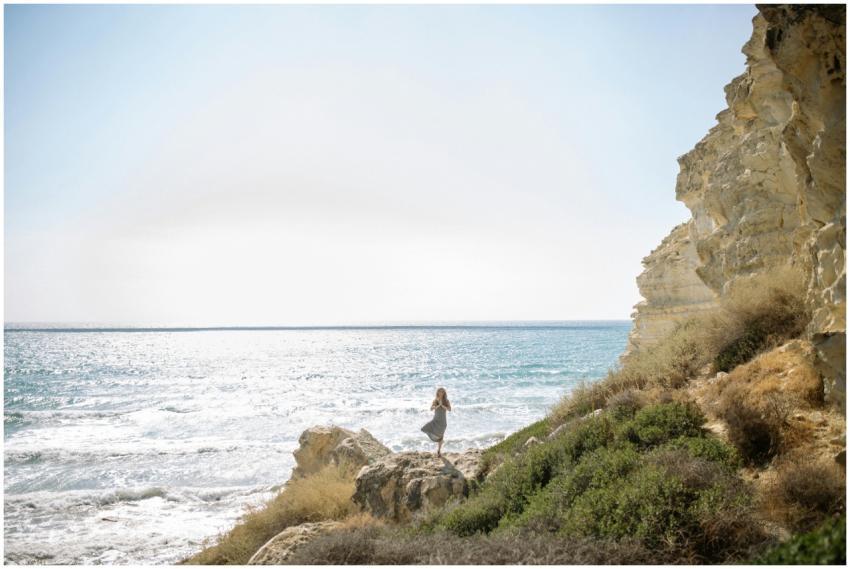 Woman standing in a yoga pose on rocks by the sea,