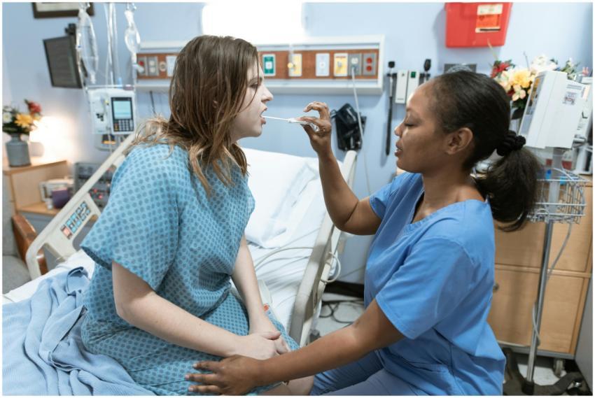 A nurse in scrubs caring for a patient in a hospit