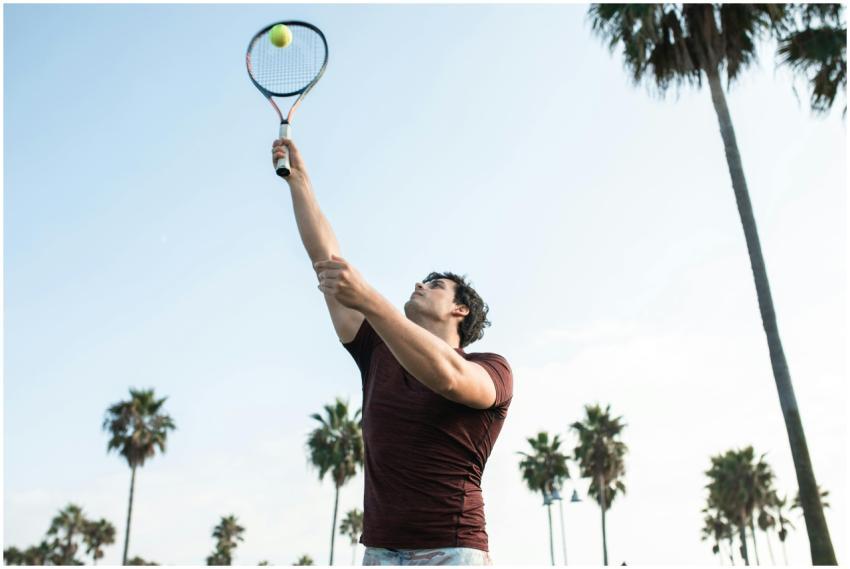 A young man playing tennis outdoors, hitting a bal