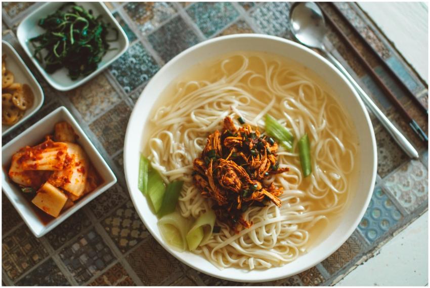 Top view of a Korean noodle soup with various side
