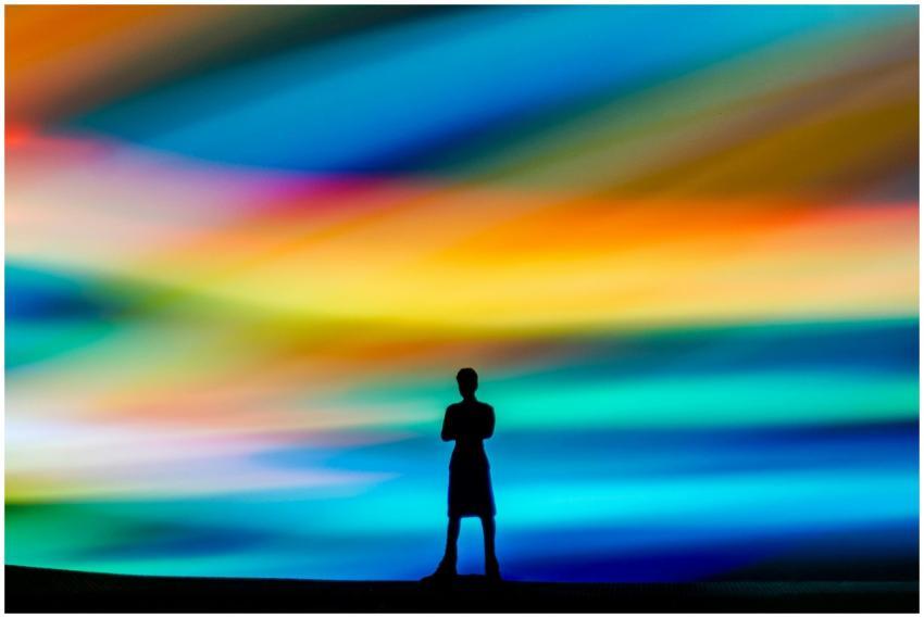 A silhouette of a person stands before a vibrant a