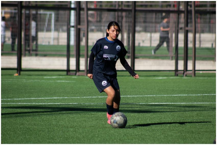A young female athlete playing soccer on a green o