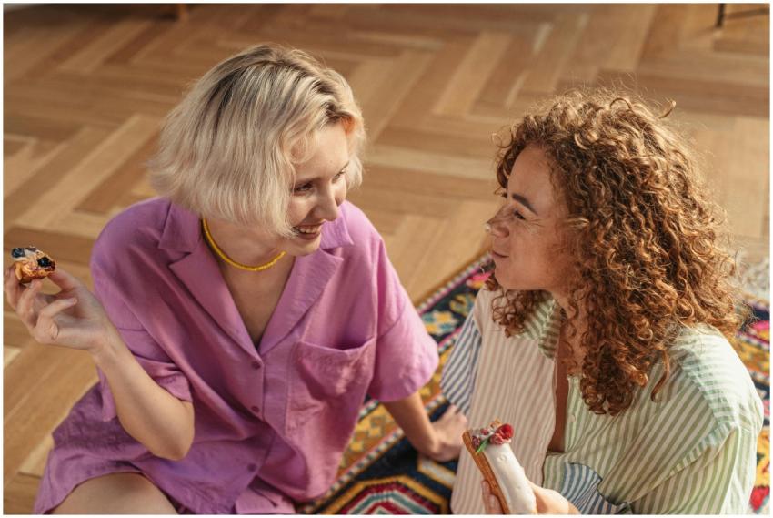 Two women sitting on the floor indoors, sharing de