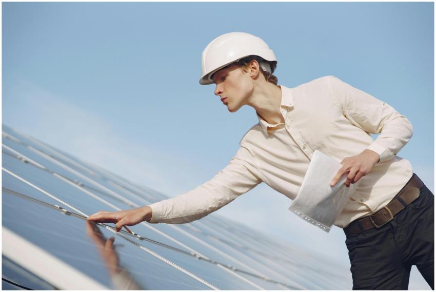 A solar technician in a hard hat inspecting photov