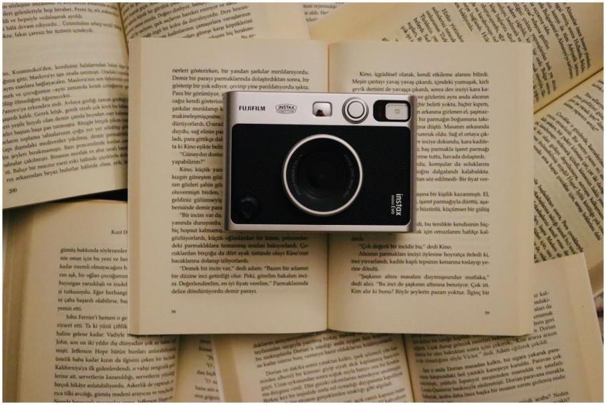 Vintage camera rests on open pages of books, creat
