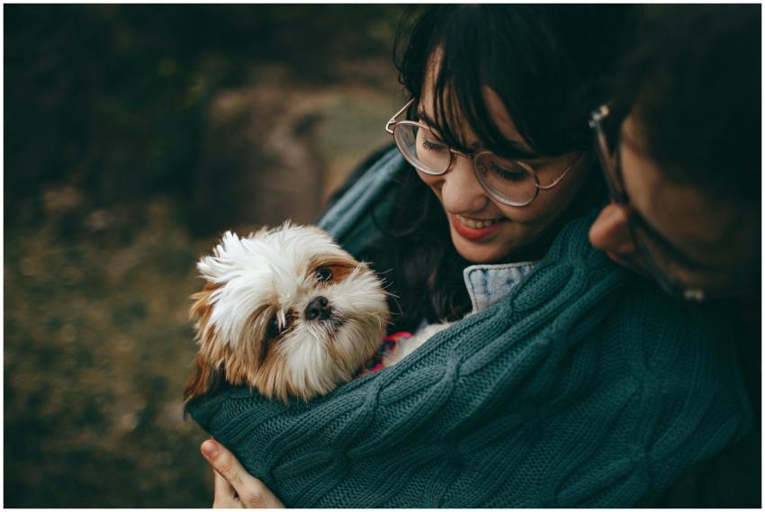 A woman lovingly cuddles her Shih Tzu puppy, wrapp