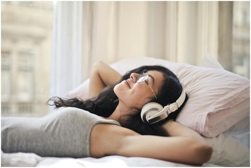 A woman with headphones lying on a bed, enjoying m