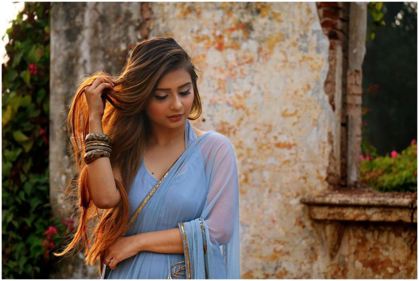 A woman in a blue saree poses gracefully outdoors