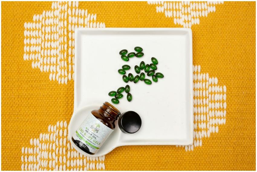 CBD oil capsules in a bottle on a white tray over