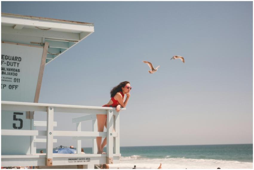 Stylish woman in red swimsuit posing at a beach li