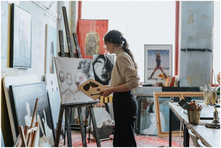A woman artist works on a painting in a creative s