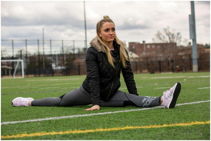 Woman doing a split in sportswear on a grass field