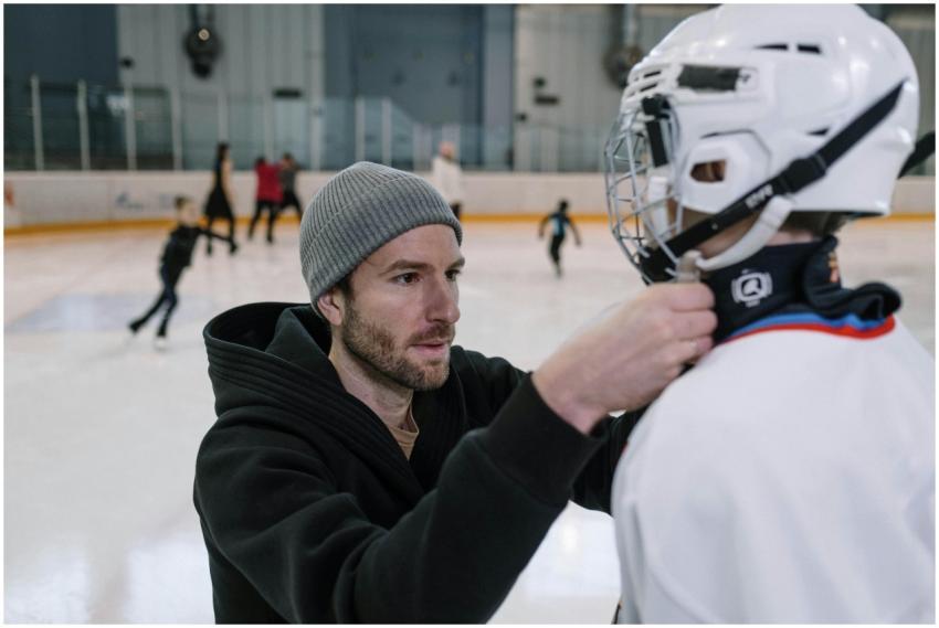 Father helps adjust son's hockey gear at an indoor