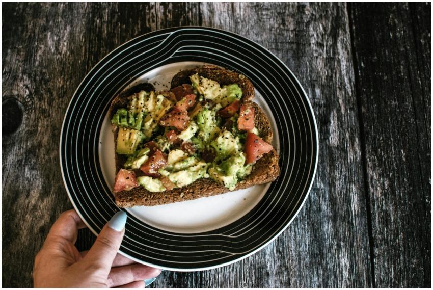 A slice of hearty avocado toast with tomatoes serv