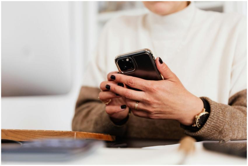 Unrecognizable woman using smartphone at her desk,