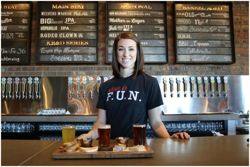 Smiling bartender in a bar serving craft beer flig