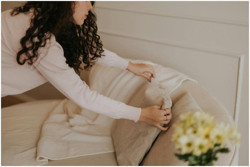 A woman arranging cushions in a cozy, minimalist l