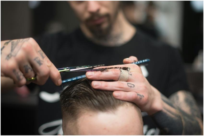 A tattooed barber provides a precise haircut in a