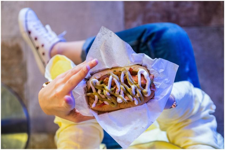 A person holding a delicious hot dog with toppings
