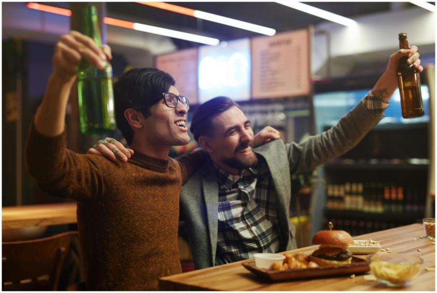 Two men enjoying drinks and food in a lively bar s