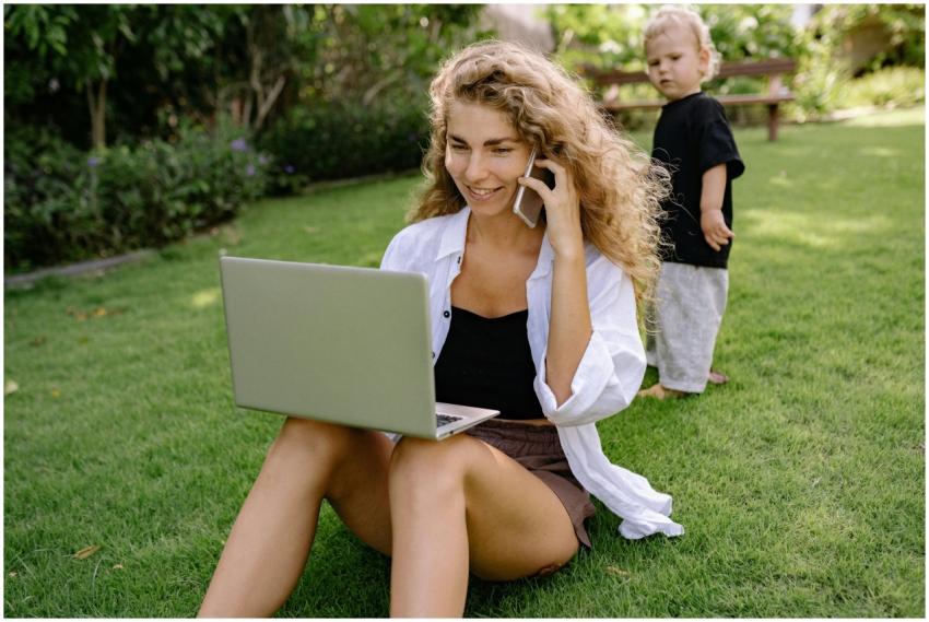 A woman multitasking with a laptop and phone while