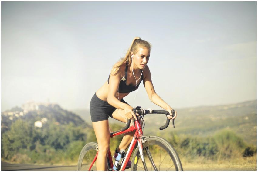 A determined woman cycling on a road with scenic v