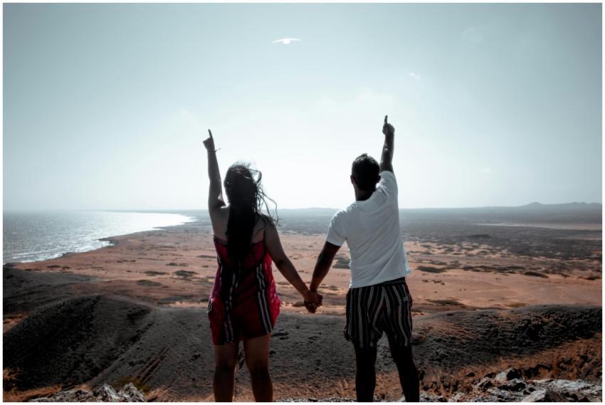 A couple holding hands and pointing at the horizon