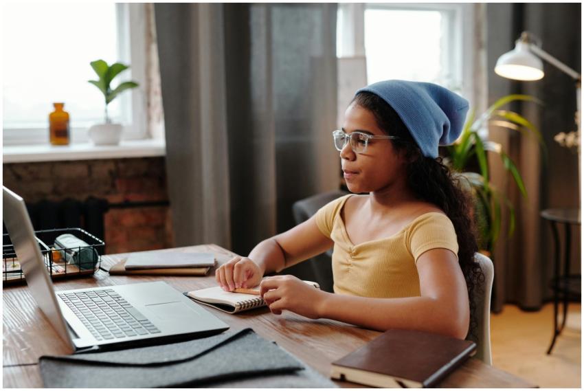 A girl sits at a desk with a laptop, engaged in on