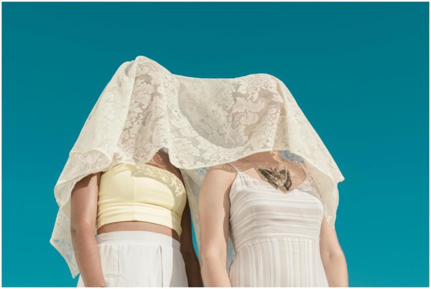 Minimalist shot of two women under a white lace ve